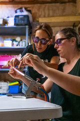 Woman in a glass jewelry creation workshop with the teacher helping her