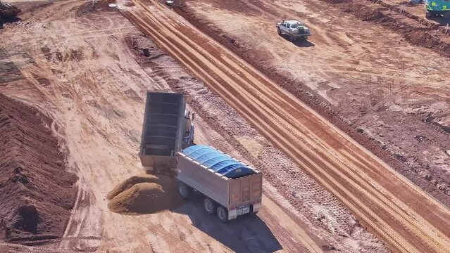 Truck and trailer tipping front bin and driving from construction site