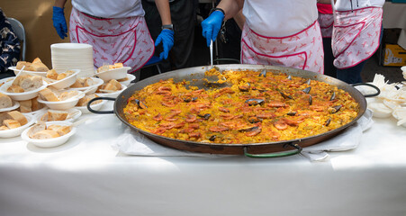 Chefs Serving Traditional Spanish Seafood Paella at Outdoor Event