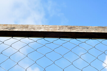 Wire fence with wooden frame blue sky background