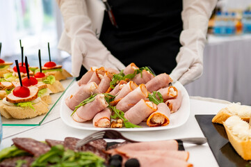 Waiter serving rolled ham appetizers at a catered event