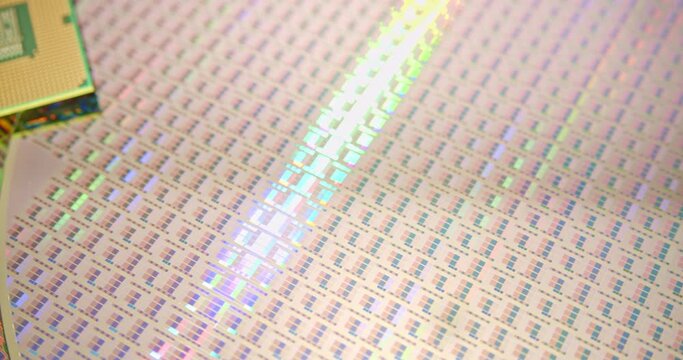 A close-up view of a silicon wafer's microprocessor circuit layout. The semiconductors or central processing unit CPU microchips are fabricated from a silicon wafer with patterned layers of materials.