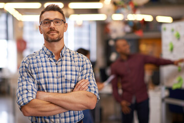 Portrait, glasses and business man with arms crossed in startup office for pride in career or job. Creative, face and confident professional entrepreneur, copywriter and employee coworking at company