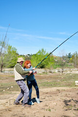 A man and a woman are fishing in a lake, they are pulling hard surprised because they got a big fish.