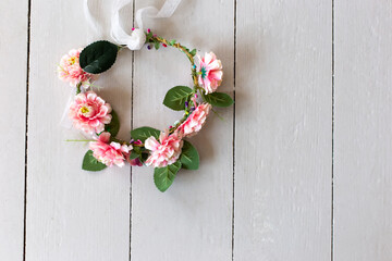 Top view of wreath of textile pink flowers lies on a white wooden table