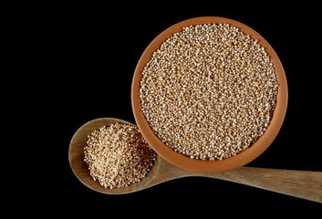 Amaranth pops in clay pot, popped grains isolated on black background, top view