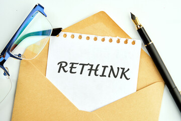 Rethink Business Concept text an inscription on a piece of paper peeking out of an envelope next to glasses and a pencil