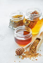 Raw organic bee pollen and honey in jars.