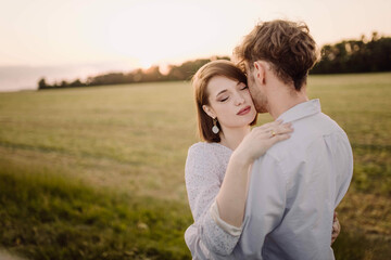 beautiful young couple in a field in the summer on a date in white clothes.