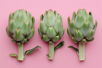 Obraz premium Three Fresh Artichokes on Pink Background