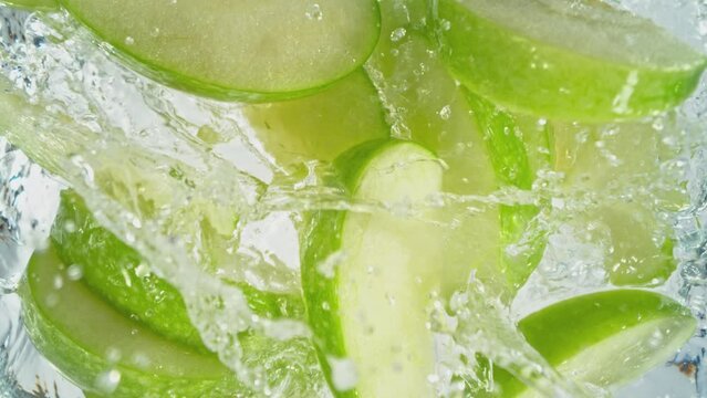 Super Slow Motion Shot of Green Apple Cuts Followed by Camera Splashing into Water at 1000 fps.