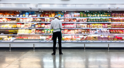 Worker male employee in an apron stands on supermarket dairy product section