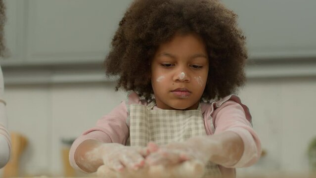 Funny Cute Little African American Girl With Dirty Flour Face Daughter Child Kid Learning Cooking Baking Cookies Using Rolling Pin Cook Dough Help Mom Unrecognizable Mother At Kitchen Food Family