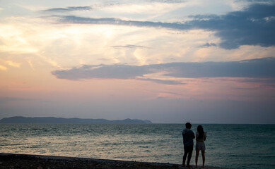 Fototapeta premium Couple standing on the beach at sunset ocean horizon