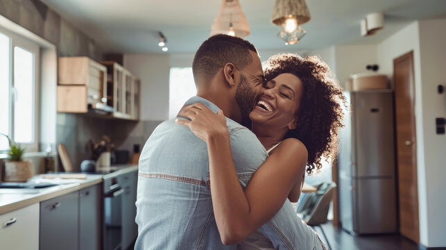 A happy young couple embraces in their new home, celebrating the joy of homeownership. The couple stands in their modern kitchen, with warm lighting and a bright atmosphere
