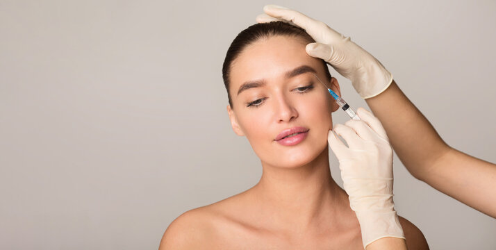 Healthcare professional administers an injection into half-naked woman face. The woman is calmly looking ahead as the procedure takes place.