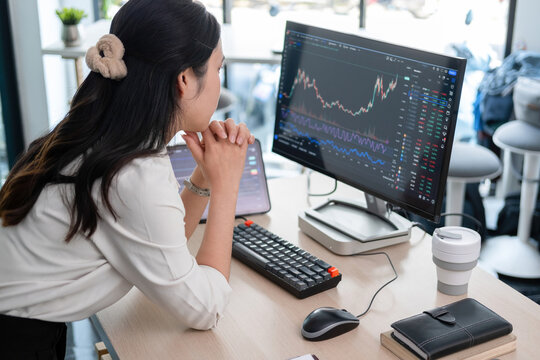 Young woman examines stock graphs at office desk