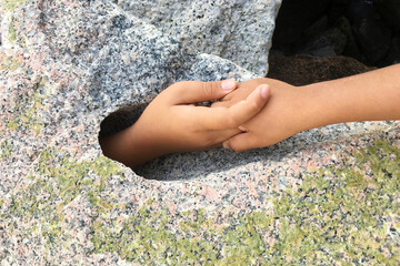 Hand request help from big stone hole.