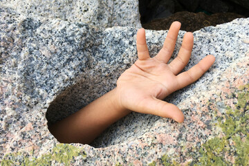 Hand request help from big stone hole.