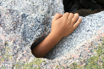 Hand request help from big stone hole.