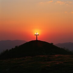 Silhouette of a cross on a hill at sunset, with the sky painted in warm hues and the sun setting behind the cross.