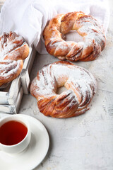 Buns with powdered sugar. Two rolls with coffee on the table.