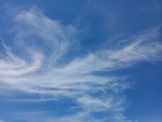 Gentle white clouds in a blue summer clear sky. Calm sky in good sunny weather with small thin clouds