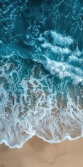 Naklejka premium Aerial view of ocean waves gently crashing onto the sandy shore, showcasing the beauty and tranquility of the coastline.