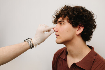 Rhinoplasty surgery preparation for man. ENT is touching nose and consulting man. Final examination...