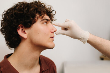 Rhinoplasty to change size or shape of nose and fix issues from injury or improve breathing problems. ENT doctor touching nose of patient before rhinoplasty or septoplasty surgery.