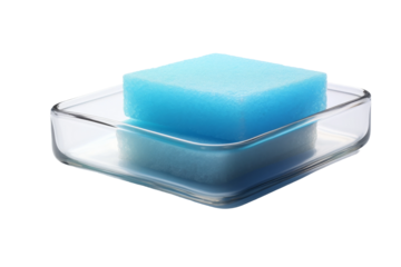 A Single Blue Bar of Soap Rests In A Clear Glass Dish on a Clear PNG or White Background.