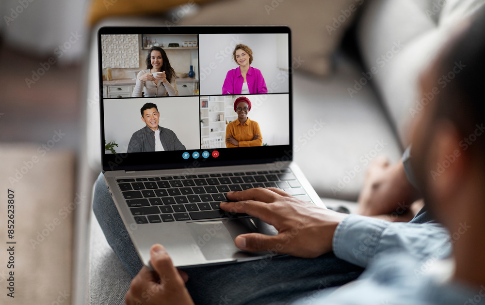Aufkleber a man sits on a couch with a laptop in his lap. the screen displays a video conference, showing four