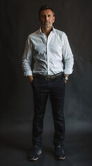 Fototapeta premium full body portrait of a middle aged business casual man with glasses and a button up shirt with a dark studio background