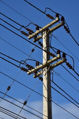 Power lines on a pole against a blue sky