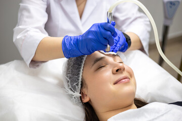 Face Beauty Treatment. Close up of female client smiling during facial microdermabrasion procedure...