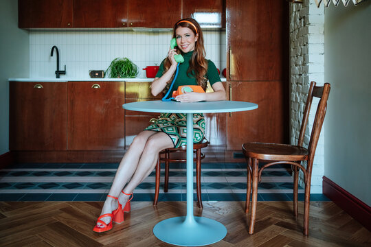 Vintage-style housewife chatting on a retro phone in the kitchen