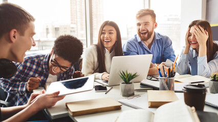 Excited friends having break in college library, preparing for lectures and laughing