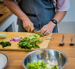 Chef at the kitchen preparing green curry with herbs and rice