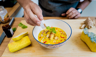 Chef at the kitchen preparing pumpkin porridge with tofu and vegetables