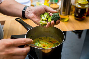 Chef at the kitchen preparing green curry with herbs and rice