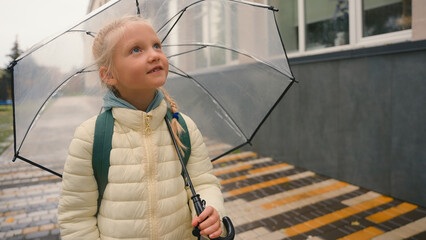 Little girl schoolgirl walking going sidewalk street city outside looking at buildings daughter...
