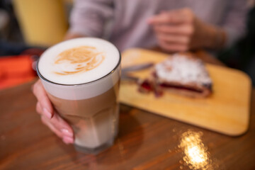woman hands with latte on a wood table in cafe
