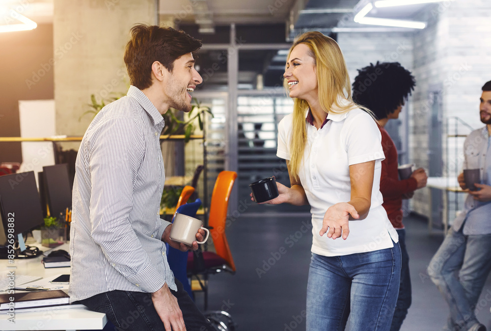 Poster a man and a woman engaged in a conversation in an office setting. they are seated at a desk, with pa