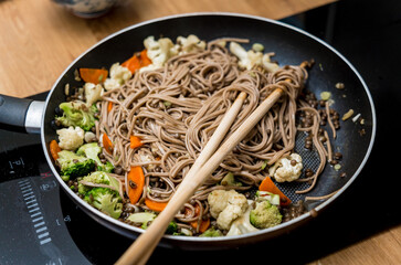 Chef at the kitchen preparing japanese buckwheat pasta with lentils