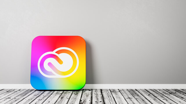 Adobe Creative Cloud App Icon on Wooden Floor Against Wall