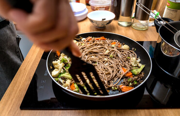 Chef at the kitchen preparing japanese buckwheat pasta with lentils