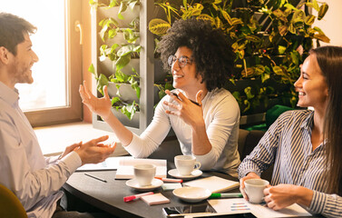 Young team interacting in cafe, inspired black guy explaining his great ideas to colleagues, free space