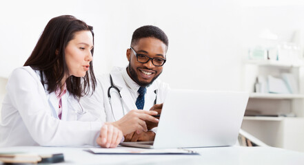 Obraz premium Two practitioners consulting, using laptop and discussing diagnosis questions in meeting room