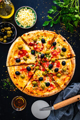 Circle pizza chorizo with black and green olives and mozzarella on wooden table
