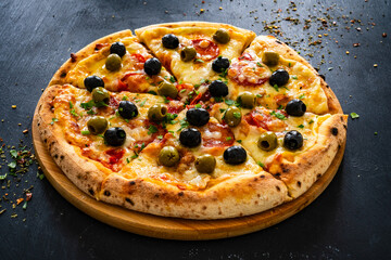 Circle pizza chorizo with black and green olives and mozzarella on wooden table
